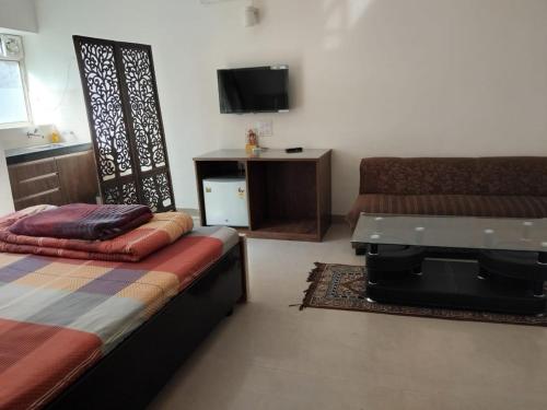 1 dormitorio con 1 cama, escritorio y TV en Newly Renovated Apartment in Omaxe - Spiritual Purpose Only, en Vrindāvan