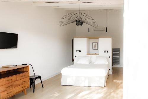 a white bedroom with a bed and a tv at Mas de la Fouque - Hôtel & Spa in Saintes-Maries-de-la-Mer