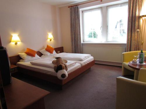 a teddy bear sitting on a bed in a hotel room at Ferien- und Reitsport Hotel Brunnenhof in Suhlendorf