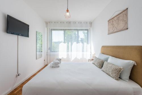 a bedroom with a large white bed and a television at GuestReady - One happy stay in Foz do Douro in Porto