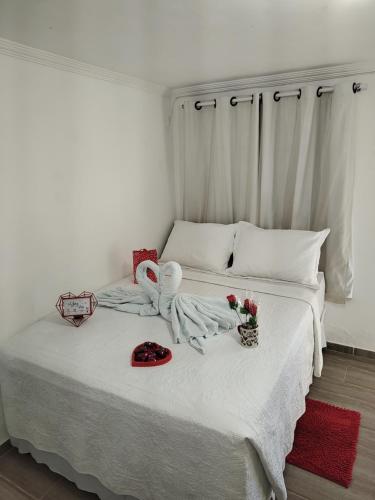 a white bed with two towels and flowers on it at Apto "Cantinho da Paula" in Maragogi