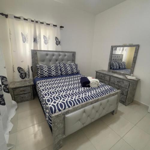 1 dormitorio con cama con edredón azul y blanco y espejo en Apartamento Bayahibe Chelsie 1, en Bayahibe