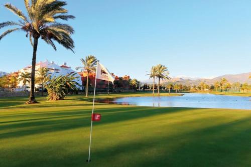 einen Golfplatz mit Palmen und einem Teich in der Unterkunft Candela Beach Luxury Apartament in Motril