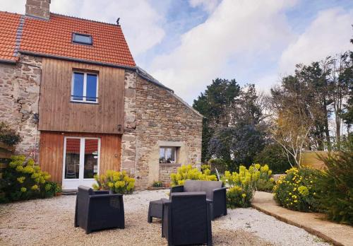 a stone house with black chairs in front of it at Gîte de la Ferme du Clos Giot in Saint-Vaast-la-Hougue