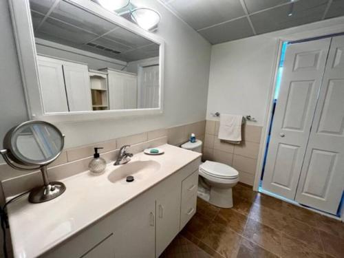 a bathroom with a sink and a toilet and a mirror at Cozy Waterfront Cottage in Victoria Harbour in Victoria Harbour