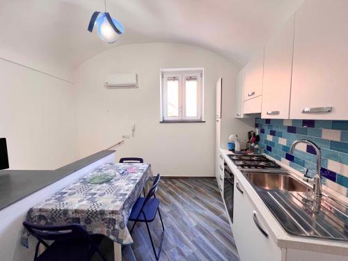 uma cozinha com uma mesa, um lavatório e um balcão em Casa vacanze centro storico Procida em Procida