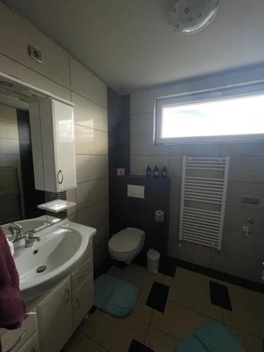 a bathroom with a sink and a toilet and a window at Korona Panzió in Balog nad Ipľom
