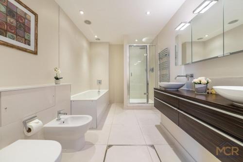 a bathroom with two sinks and a toilet and a tub at Royal 4 Bedroom Apartment in Mayfair in London