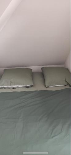 a white bed with two pillows on top of it at Le petit Treguier in Tréguier