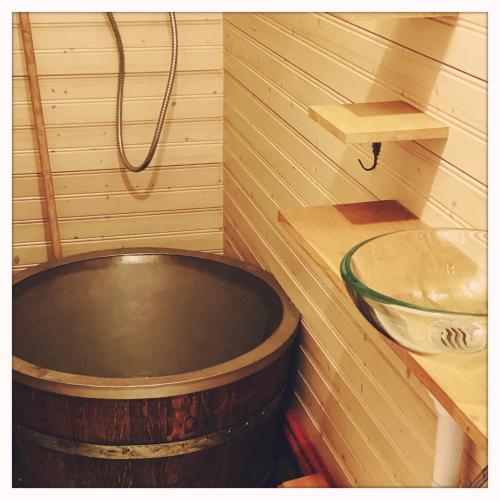 La salle de bains est pourvue d'une grande baignoire en bois et d'un lavabo. dans l'établissement Roulotte enchantée dans le parc d'un château vendéen, à Sevremont