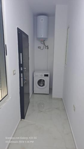 een kleine witte kamer met een wasmachine en een deur bij Casa Sarà in Pogradec