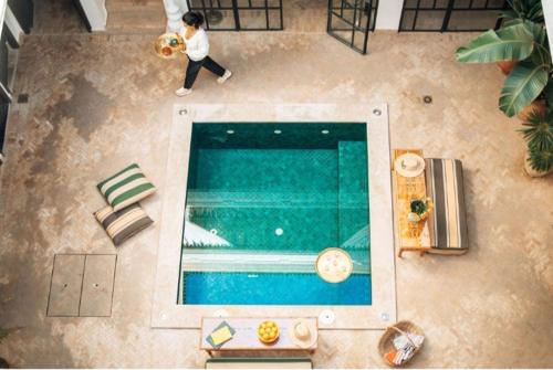 a person walking by a swimming pool with a dog at Riad Deha & Spa in Marrakesh