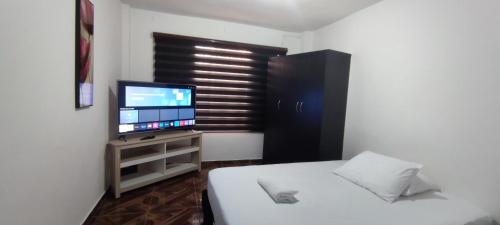 1 dormitorio con 1 cama y TV de pantalla plana en Hermoso apartaestudio, en Pitalito