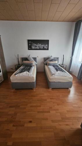two beds sitting in a room with a wooden floor at Suite Toni in Bernburg