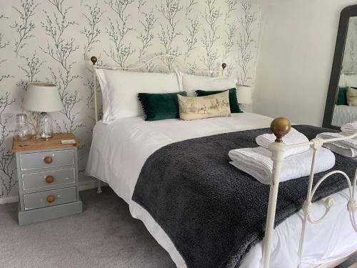 een slaapkamer met een wit bed met een zwarte deken en een spiegel bij Tiny romantic cottage for two. in Lostwithiel