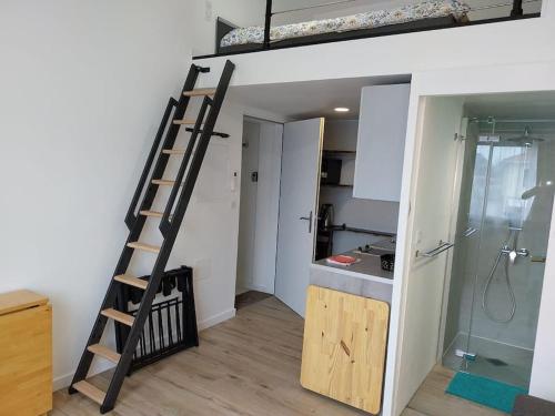 uma escada num quarto com uma cozinha e uma cama alta em studio Indépendant et climatisé. arrivée autonome em Bègles