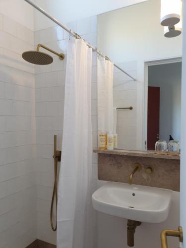 uma casa de banho com um lavatório e um chuveiro com um espelho. em Monte das Açoteias - Agroturismo em Tavira