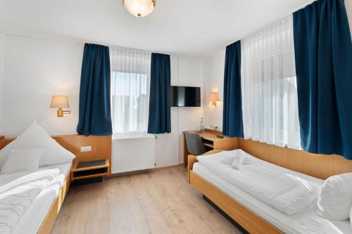 una camera d'albergo con due letti e tende blu di Hotel Garni Traube a Friedrichshafen