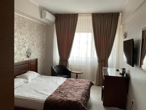 a bedroom with a bed and a chair and a window at Hotel Ana in Constanţa