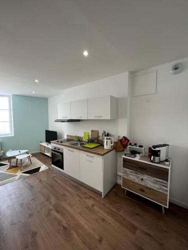 a kitchen with white cabinets and a wooden floor at La maison castelpontine studio 2 in Pont-du-Château