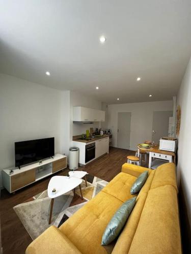 ein Wohnzimmer mit einem gelben Sofa und einer Küche in der Unterkunft La maison castelpontine studio 2 in Pont-du-Château