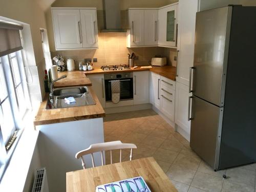 a kitchen with white cabinets and a sink and a refrigerator at Cottage in Ayr