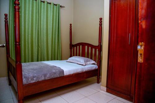 Un dormitorio con una cama y una cortina verde. en Beautiful 2-Bed house in Kampala, en Jinja