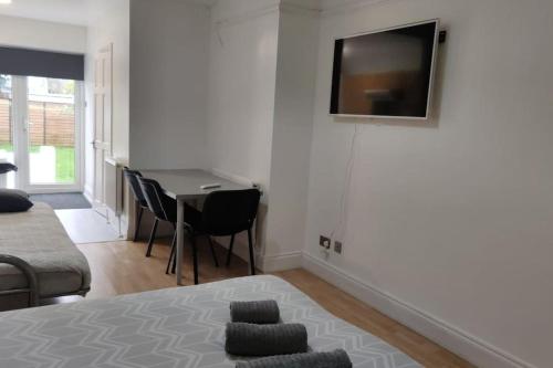 a bedroom with a bed and a table with a television on the wall at Large Studio Garden Flat on Golders Green Road in London