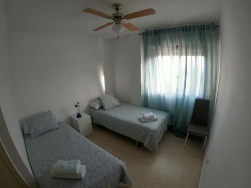 a bedroom with two beds and a ceiling fan at Piso Feria de Abril in Fuengirola