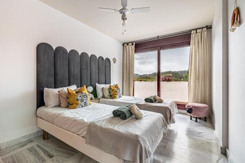 two beds in a bedroom with a large window at RentitSpain Charming Apartment in Parque Botanico Resort & Country Club, Marbella, Estepona, Benahavis in Estepona
