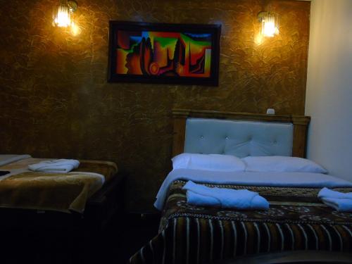 a bedroom with two beds and a painting on the wall at Hotel Restaurante El Madroño Chia in Chía