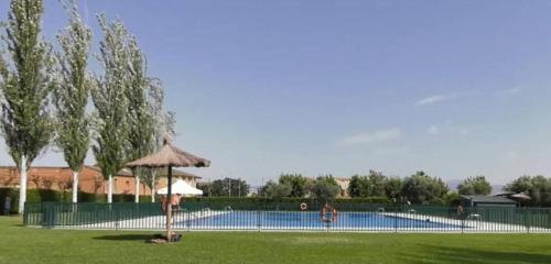a swimming pool with a umbrella in a park at Alojamiento Rural El Castillo in Agoncillo
