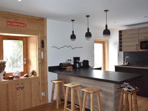- une cuisine avec un comptoir noir et des tabourets dans l'établissement Appartement cosy 3 pièces - 6 personnes, balcon, centre, proche commerces et téléphérique - FR-1-464-12, à Pralognan-la-Vanoise