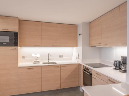 une cuisine avec des armoires en bois et un évier dans l'établissement Duplex neuf proche pistes, 400m centre, 2 chambres, parking, wifi - FR-1-645-58, à Huez