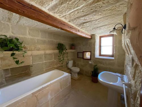 a bathroom with a bath tub and a sink at Soluna Boutique Guesthouse in Għasri