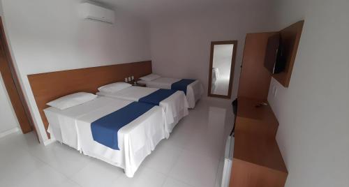 a bedroom with two beds and a television in it at NOVO HOTEL in Conceição do Coité