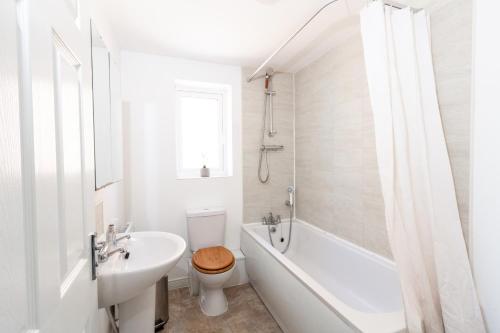 een witte badkamer met een bad, een toilet en een wastafel bij Spacious 3BR House with Garden & Free Parking in Manchester