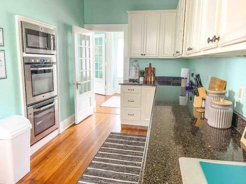 a kitchen with green walls and white cabinets at Timeless Charm: Discover the 1918 CE Smith House! in Little Rock