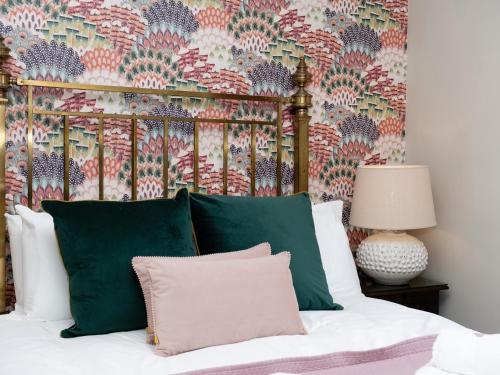 Una cama con almohadas verdes y blancas y un papel pintado. en Watermouth Castle, Bassett Apartment, en Ilfracombe