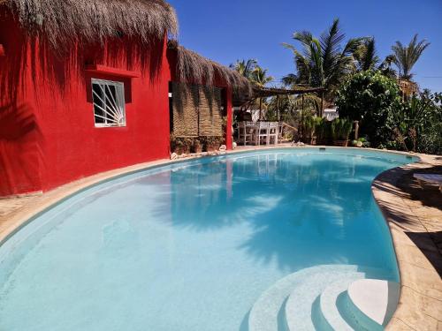 una gran piscina junto a un edificio rojo en la Maison rouge en Toliara