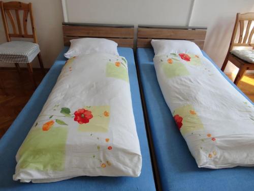 two beds with white sheets with flowers on them at BEST LOCATION IN BUDAPEST! in Budapest