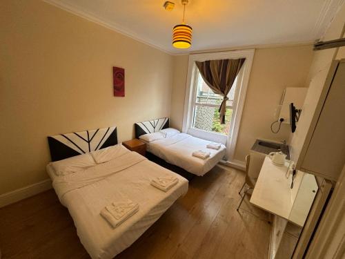 a room with two beds and a window at Anwar House in London