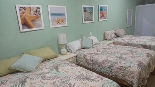 two beds in a room with pictures on the wall at Casa Amelia in San Blas