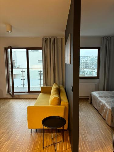 a living room with a yellow couch and a bed at Altoria Active Gdynia in Gdynia