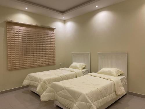 شقه غرفتين نوم وصاله ومجلس ومطبخ في الرياض: سريرين في غرفة نوم مع بطانيات ووسائد بيضاء