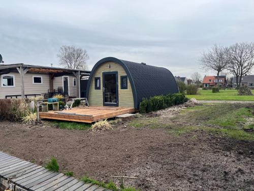 Belt-Schutsloot的住宿－Camping pod Tiny House aan het water，圆顶房子,在院子里有甲板