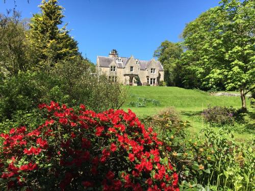 una casa vieja en una colina con flores rojas en Whitchester Christian Centre en Hawick