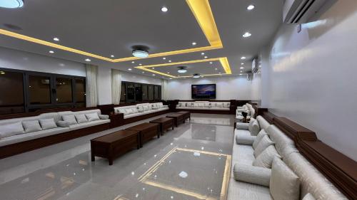 Cette grande chambre dispose de canapés, de tables et d'une télévision. dans l'établissement استراحة روضة الوادي, à Nizwa