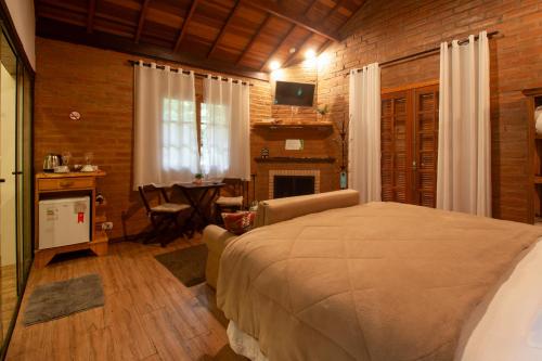 a bedroom with a bed and a living room with a table at Pousada das Acácias in Camanducaia
