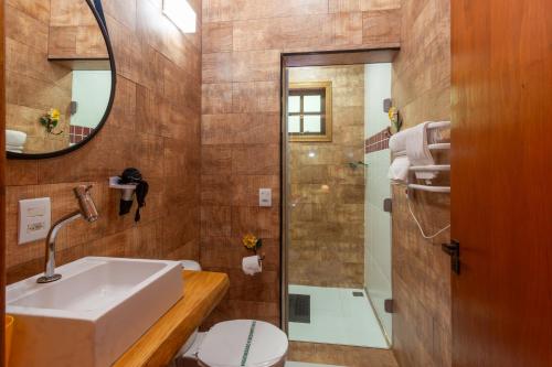 a bathroom with a sink and a toilet and a mirror at Pousada das Acácias in Camanducaia